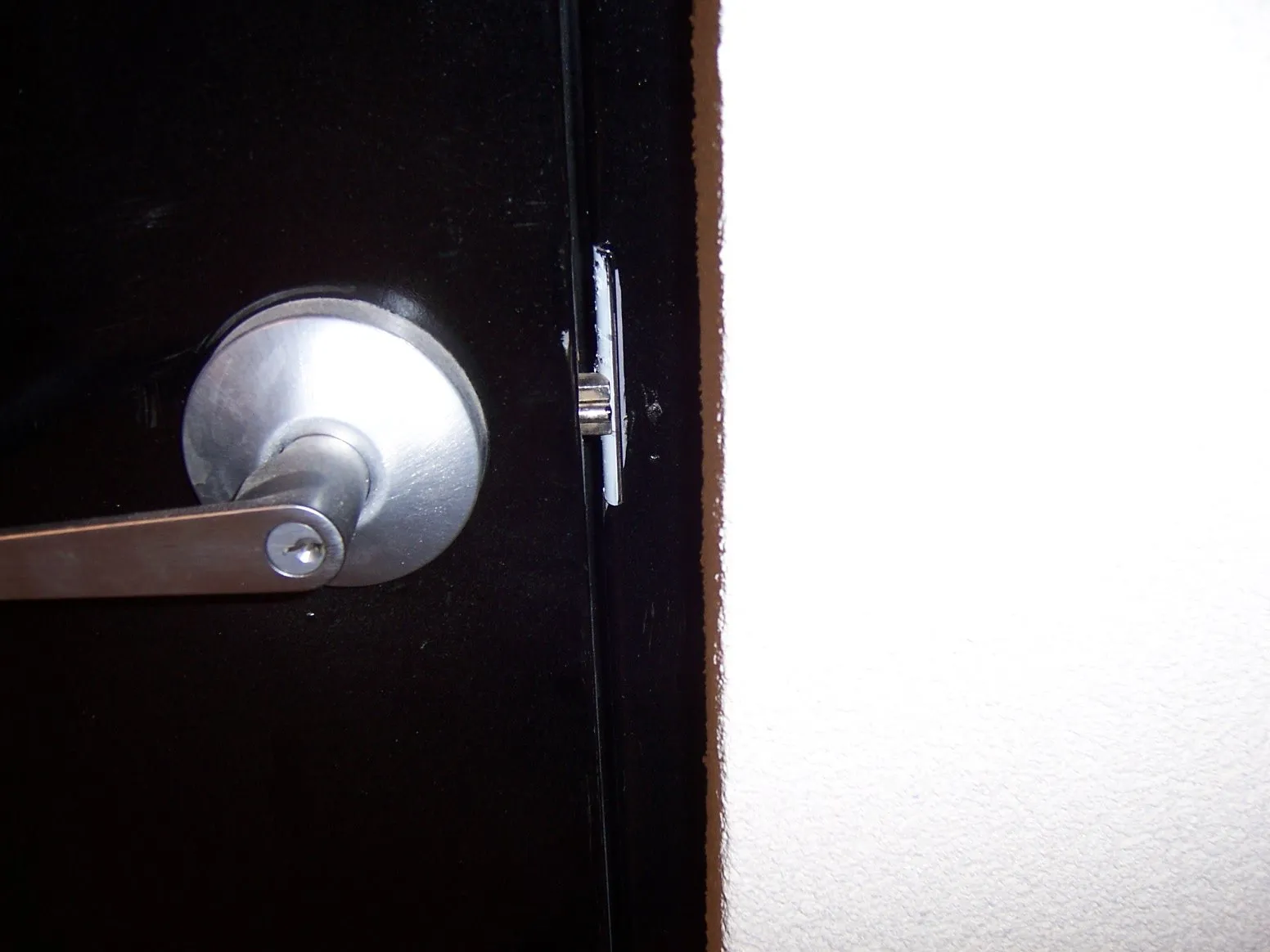 Close-up of a brushed steel lever handle on a black steel door