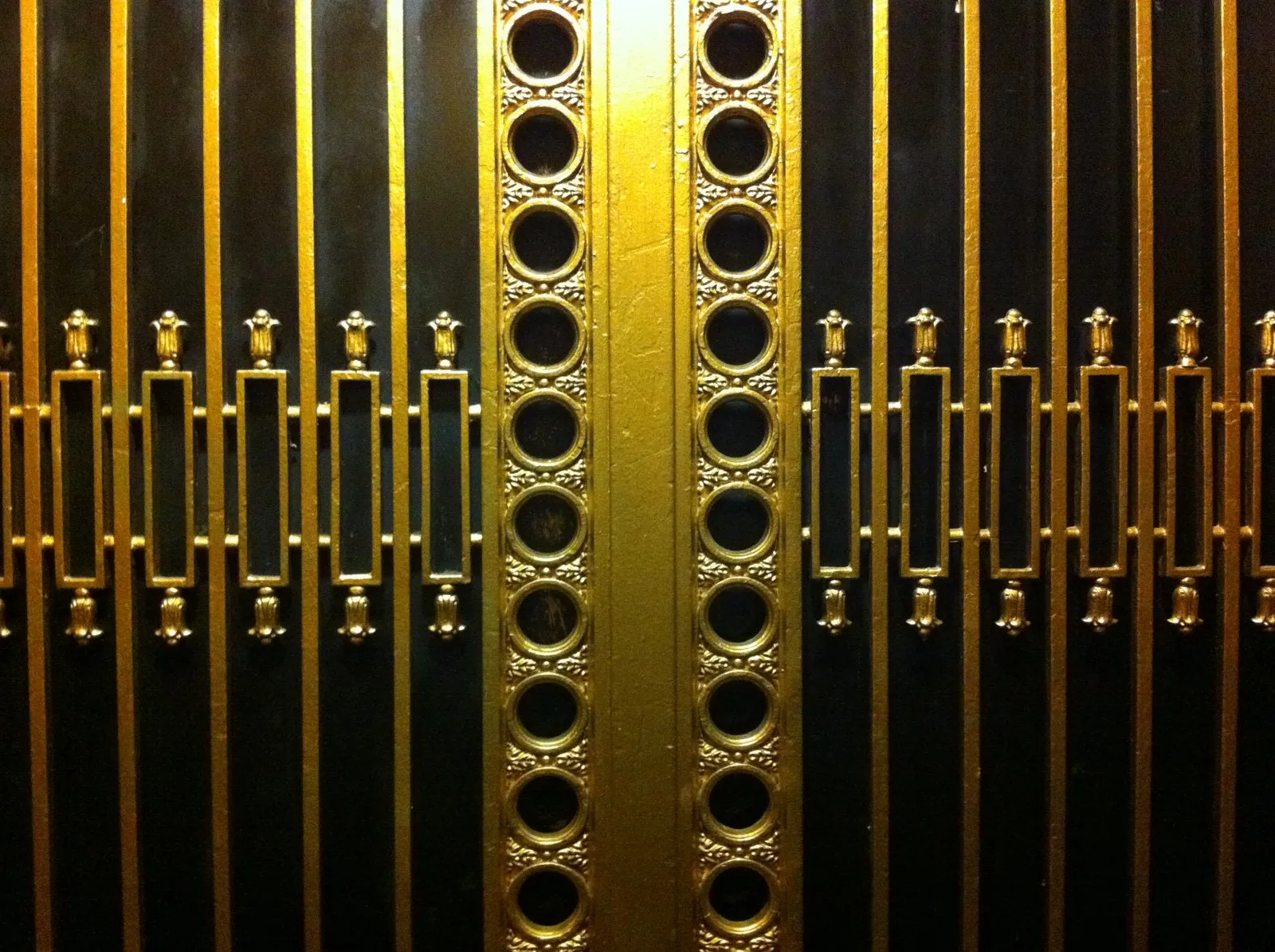 Close-up of a black and gold ornamental elevator door grille